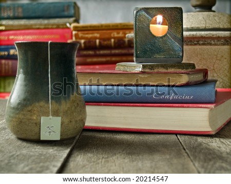 Cup of tea surrounded by old books. Shallow DOF, the focus point is a book with the name \