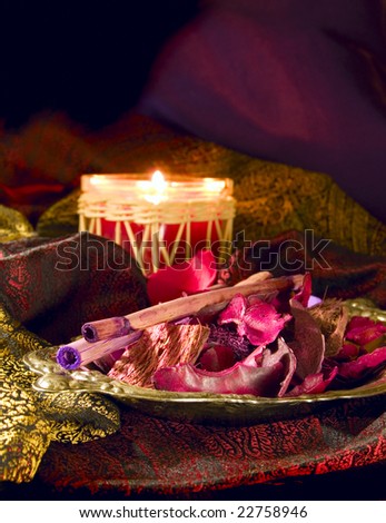 Red candle with red potpourri on sensuous fabric - still life