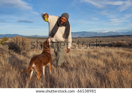 Casual African American man playing with his dog outdoors