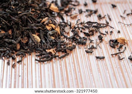 Heap of Dry tea leaves spread on light brown color background