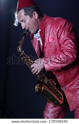 Adult man in red jacket playing the saxophone