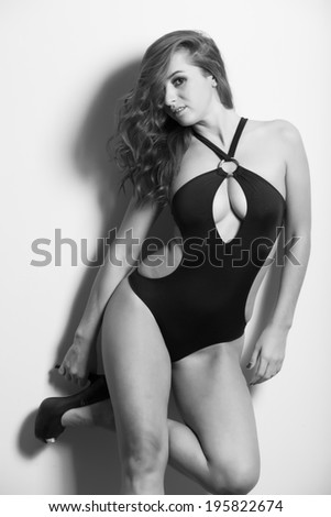 Beautiful brunette in black swimsuit studio light background