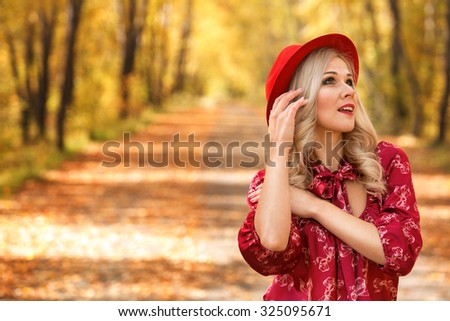 attractive girl in a red hat walks in autumn park