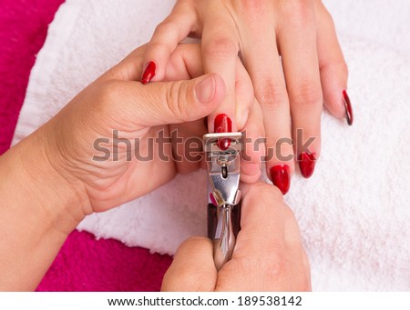 Woman receiving manicure in a  Spa, hand nails get cut and filed.
