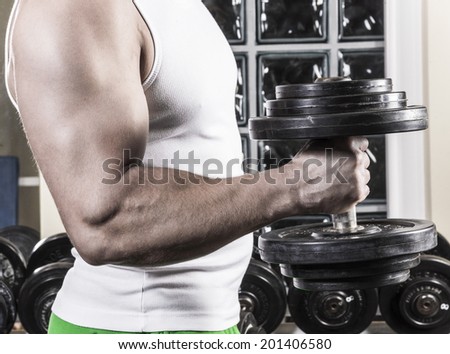Fitness man holding dumbbells in a fitness room.