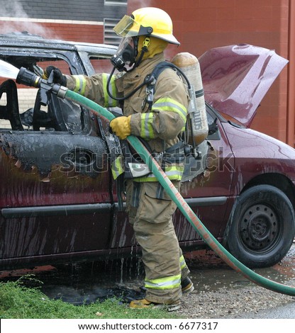A firefighter hoses down a van which caught fire.