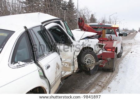A tow truck hauls away a car from an accident scene.