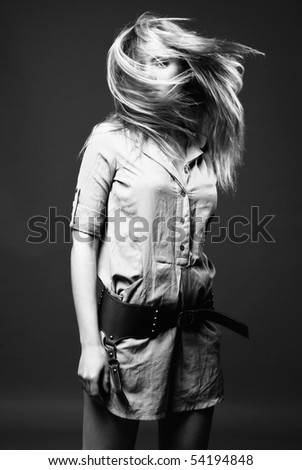 Black and white fashion portrait of young woman with flying hair on dark background