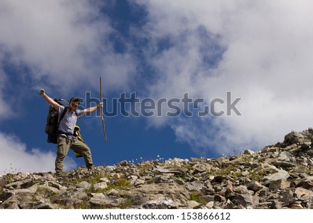 happy hiker with stick on a background of sky