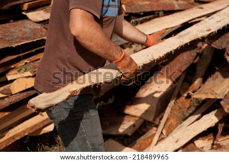 a carpenter carrying a large wood plank on his hands