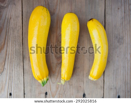Fresh summer vegetables, yellow zucchini on rustic wooden background, top view