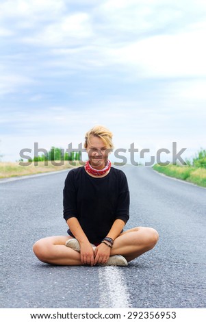 Young woman in black T-shirt smile in lotus position in the road