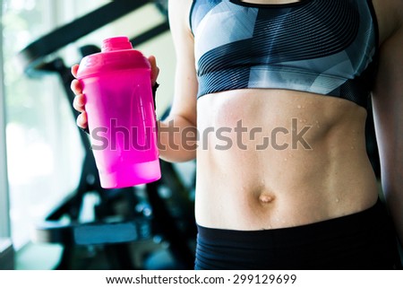 Fitness girl with pink bottle of water close up