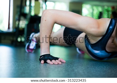 Pretty blond woman doing push-ups in the gym close up hand