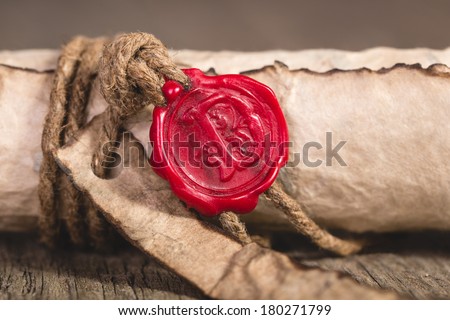 Old scroll paper on wooden background. Close up of wax seal.