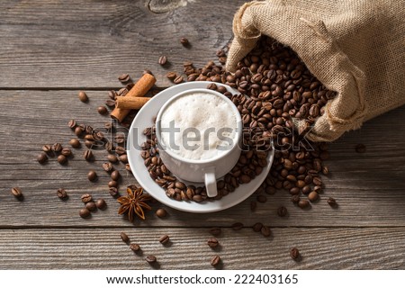 Coffee cup with cinnamon sticks and coffee bag on wooden table. View from above.