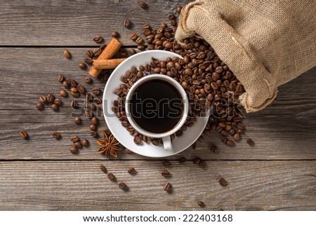 Coffee cup with cinnamon sticks and coffee bag on wooden table.View from above.