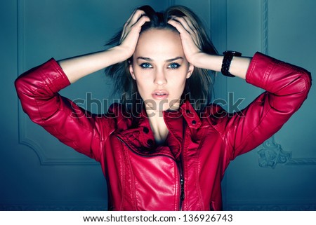 Portrait of beautiful sexy girl wearing red coat with hands over head