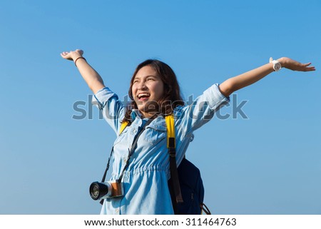 asian woman backpack travel with camera and put her hand in the air
