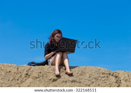 young woman working with laptop on the mountain with blue sky background