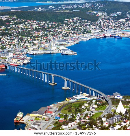 Houses, bridge and panorama of Norwegian city Tromso beyond the Arctic circle from mountain in Norwegian fjords.
