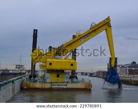 ANTWERP, BELGIUM, FEBRUARY 18, 2014: Digger is excavating sediments from the river bed inside the port of antwerp.