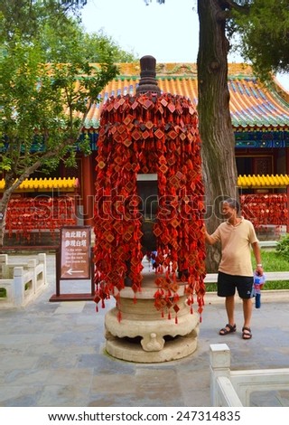 BEIJING, CHINA, AUGUST 20, 2013: chinese man is hanging his wish on the colorful hanger where hundreds of wishes already wait for fulfillment.