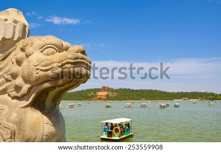 BEIJING, CHINA, AUGUST 15, 2013: detail of lion statue with kunming lake behind it in the new summer palace complex in beijing.