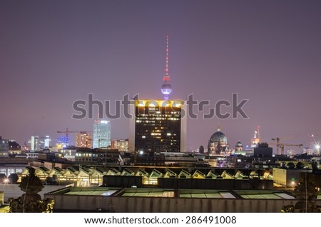 view of berlin skyline taken from the terrace of reichstag during night. fernsehturm is hidden behind a shopping center.