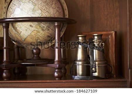 Vintage binoculars with globe on wooden rack