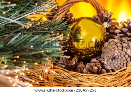 New year composition with basket with pine cones and gold Christmas ball near  the fireplace