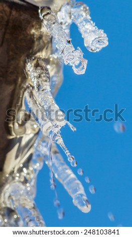 Icicles and falling droplets on a background of blue sky