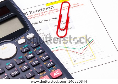 Finance report sheet with calculator and red clip