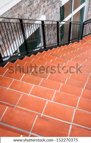 Curve stairs decorated with orange stone pile with black iron handrail