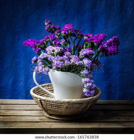 Bunch of purple flower decorated in classic white vase on wooden table with dark blue background