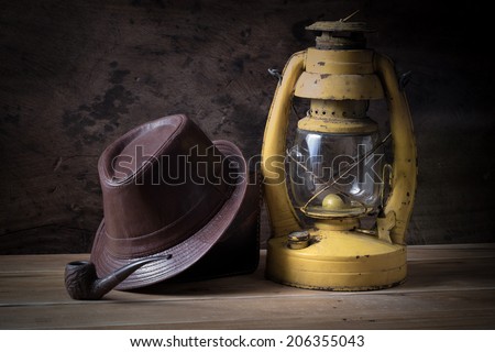 Still life vintage old lantern with leather hat and smoking pipe