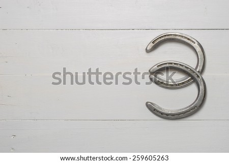 Old cast iron metal Western horse shoeing accessory horseshoes on white wood plank background