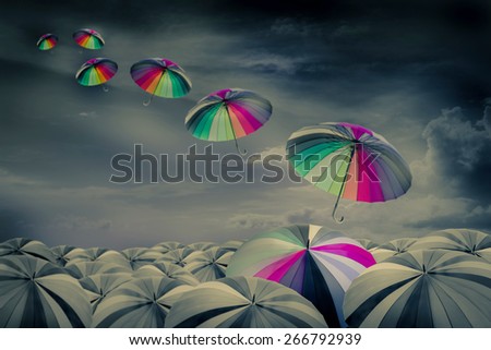 rainbow umbrella in the mass of black umbrellas