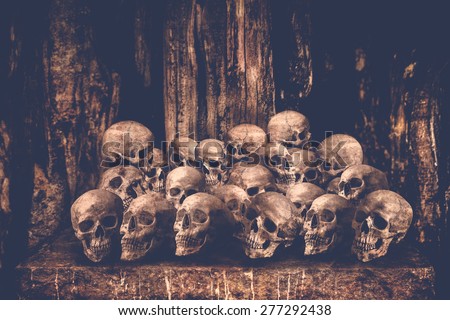 Pile of human skulls on stone table for sacrifice with golden and candle wax