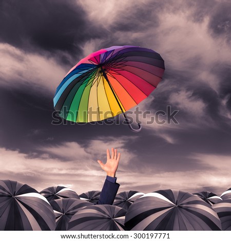 rainbow umbrella fly out from the business man hand amoung the mass of black umbrellas