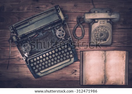 Top view of  old typewriter, telephone and book on wooden background