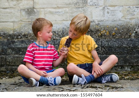 Two brothers sharing an ice lolly