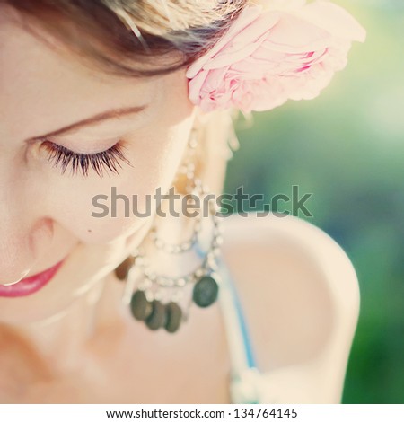 Portrait of Sensual Young Beautiful Woman with pink rose in her hair on a green background