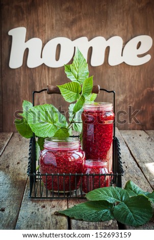 Raspberry Jam in a jars on the wooden background, decorated with world Home