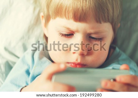 Little Boy Playing on Smartphone, Sitting in Room, toned image