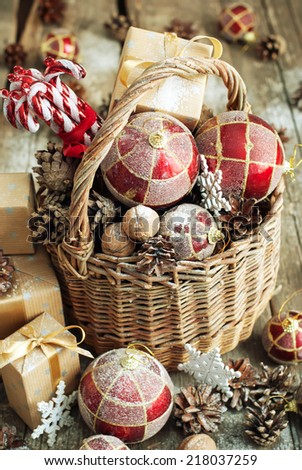 Vintage Gifts in Christmas Composition with Basket, Red balls, Pine cones, Sweet Candy toys, Pine cones, Boxes, Walnuts and snowflakes. Country style.with toned effect