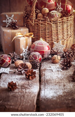 Vintage Christmas Gifts with Basket, Red balls, Pine cones, Boxes, Walnuts and snowflakes on Wooden Table. Country style, toned