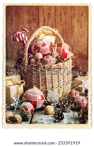 Gifts in Christmas Composition with Basket, Red balls, Pine cones, Sweet Candy toys, Pine cones, Boxes, Walnuts and snowflakes. Vintage Card. Retro Frame. Toned effect. Isolated on White