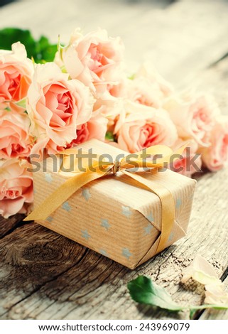 Bouquet of Tender Pink Roses with Present Box on Wooden Table in sunshine light, toned image