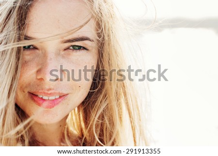 Beautiful Smiling Woman Looking at Camera with Hair Blowing in the Wind. in Sunlight. Warm Color Toned